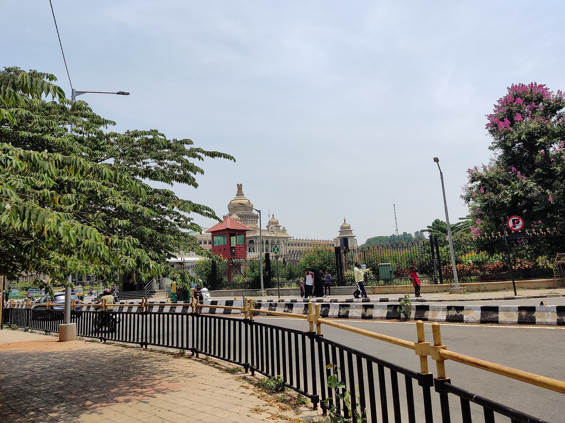 Bangalore Palace | Indian Press Bangalore Palace stands prominently amidst lush greenery and a city street, showcasing Indian architecture.