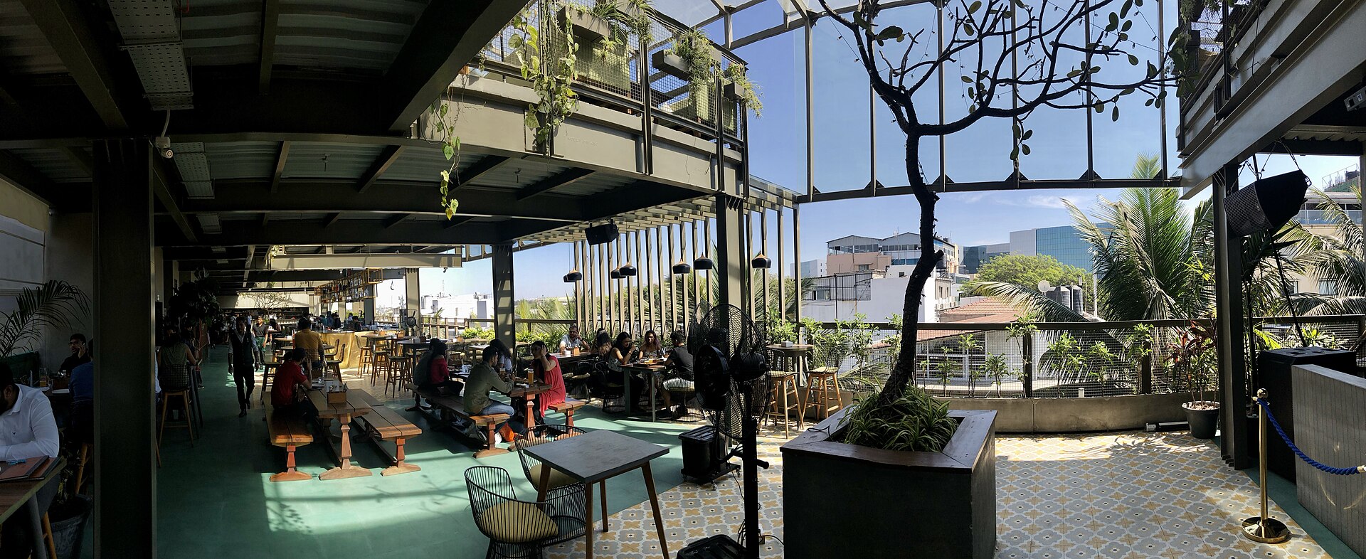 A rooftop bar in Bangalore shows the vibrant startup scene with outdoor seating and plants.