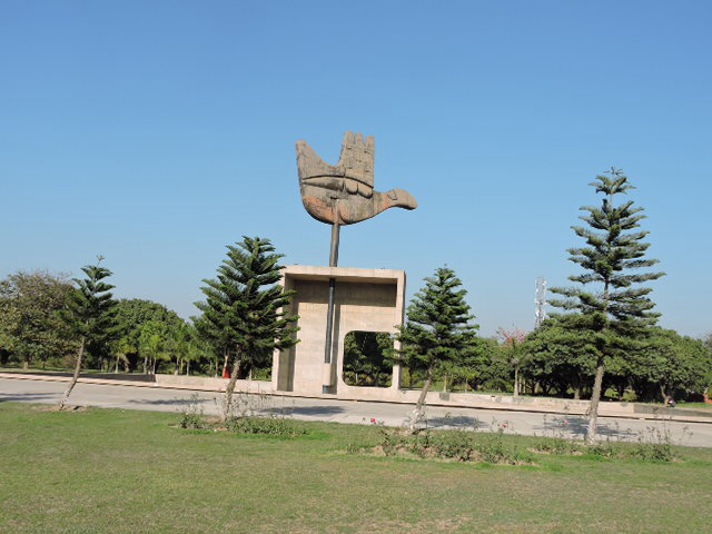 Chandigarh Open Hand | Indian Press A monument featuring a stylized bird sculpture stands within a landscaped park, showcasing Indian architecture.