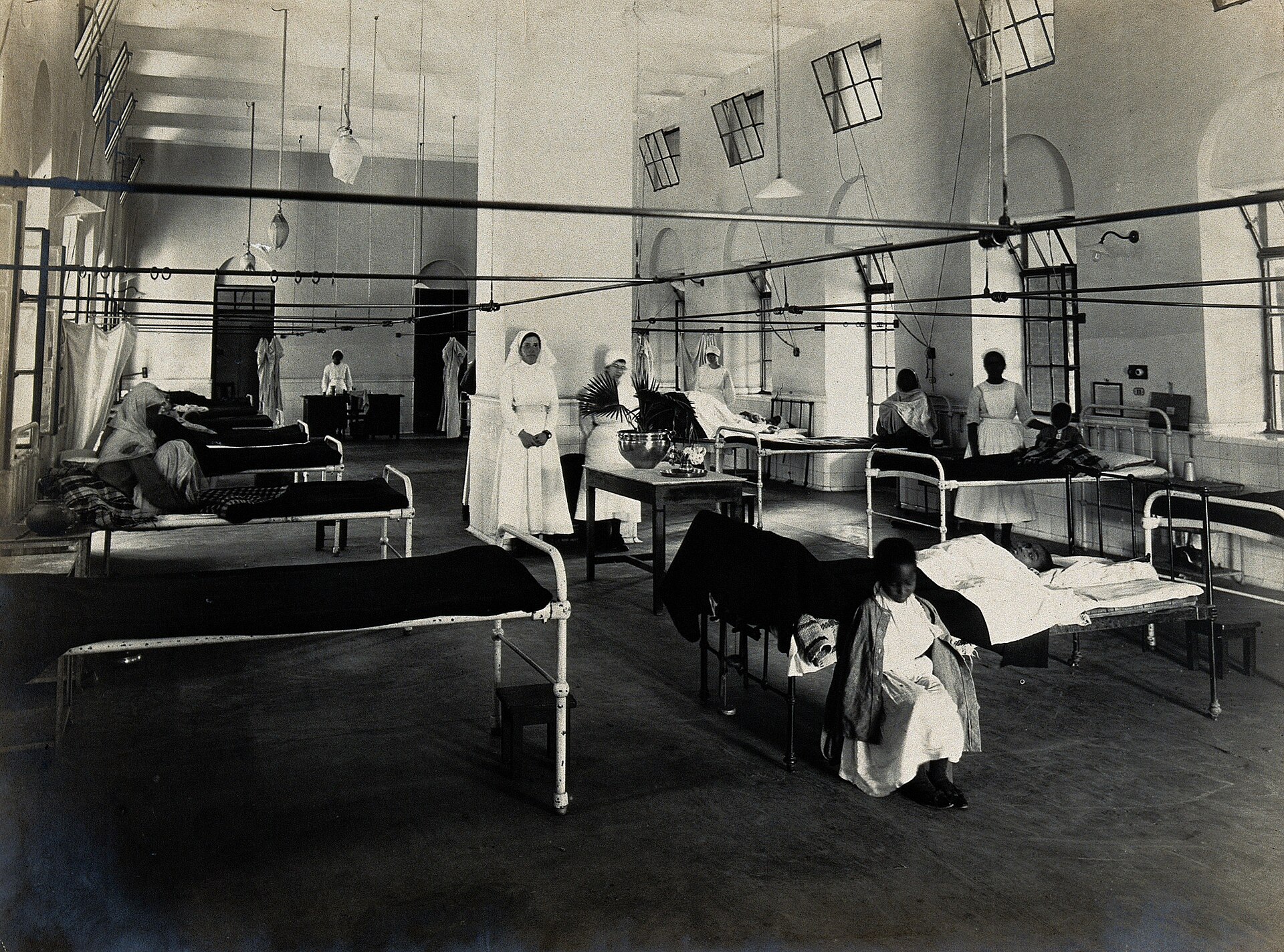 A busy hospital ward shows nurses providing medical care to patients.