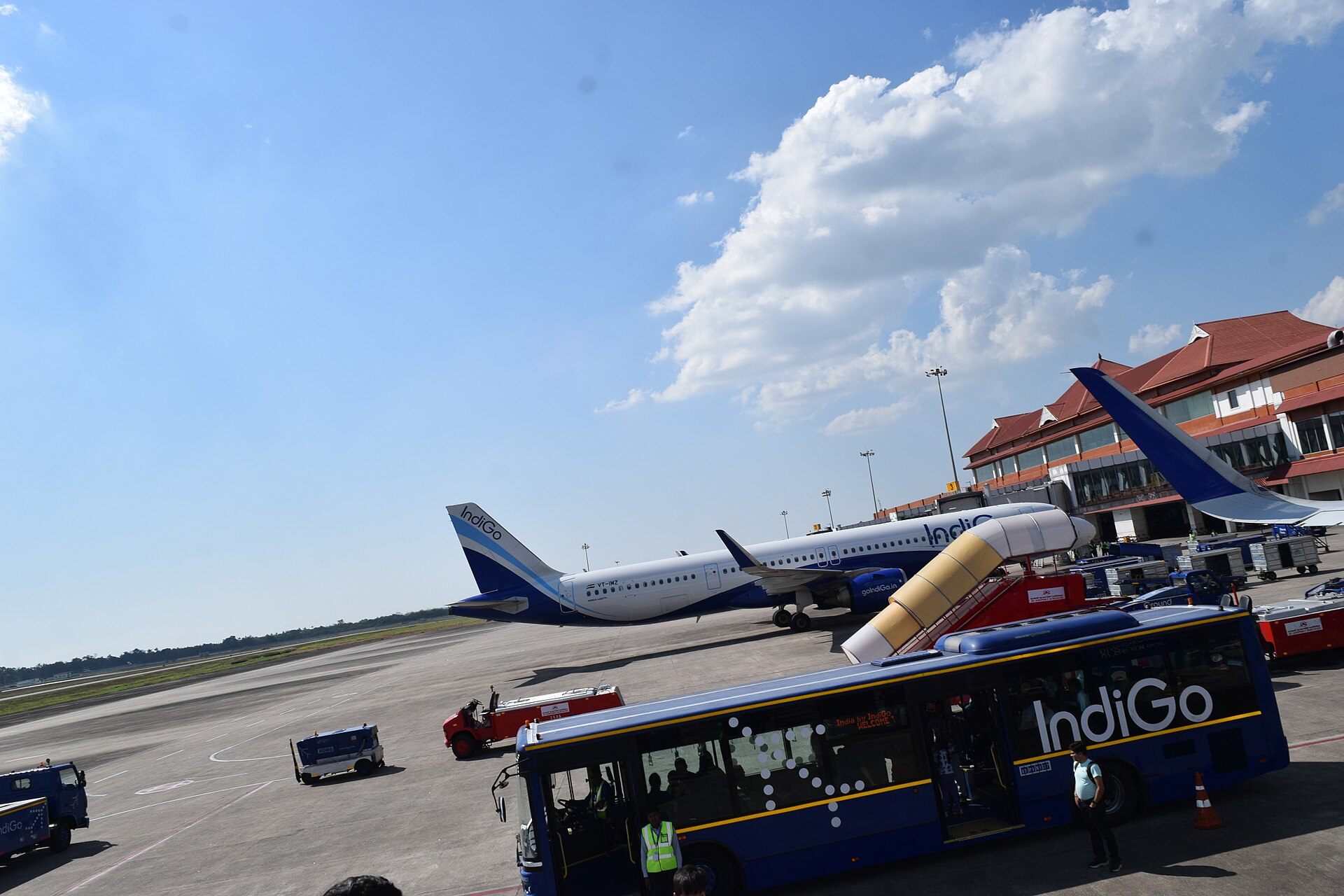 An Indigo aircraft is serviced on the tarmac at an airport, illustrating topics around remittances and migration.