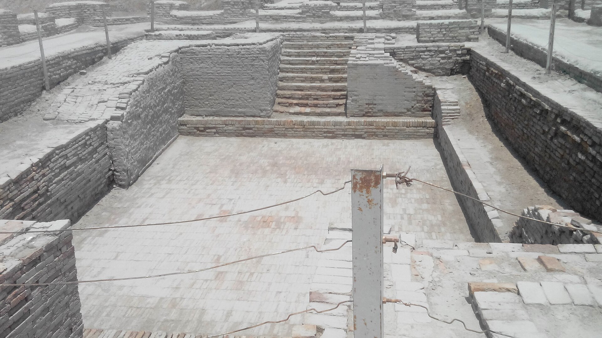 The Great Bath at Mohenjo-daro shows ancient brick ruins covered in snow, highlighting India's rich history.