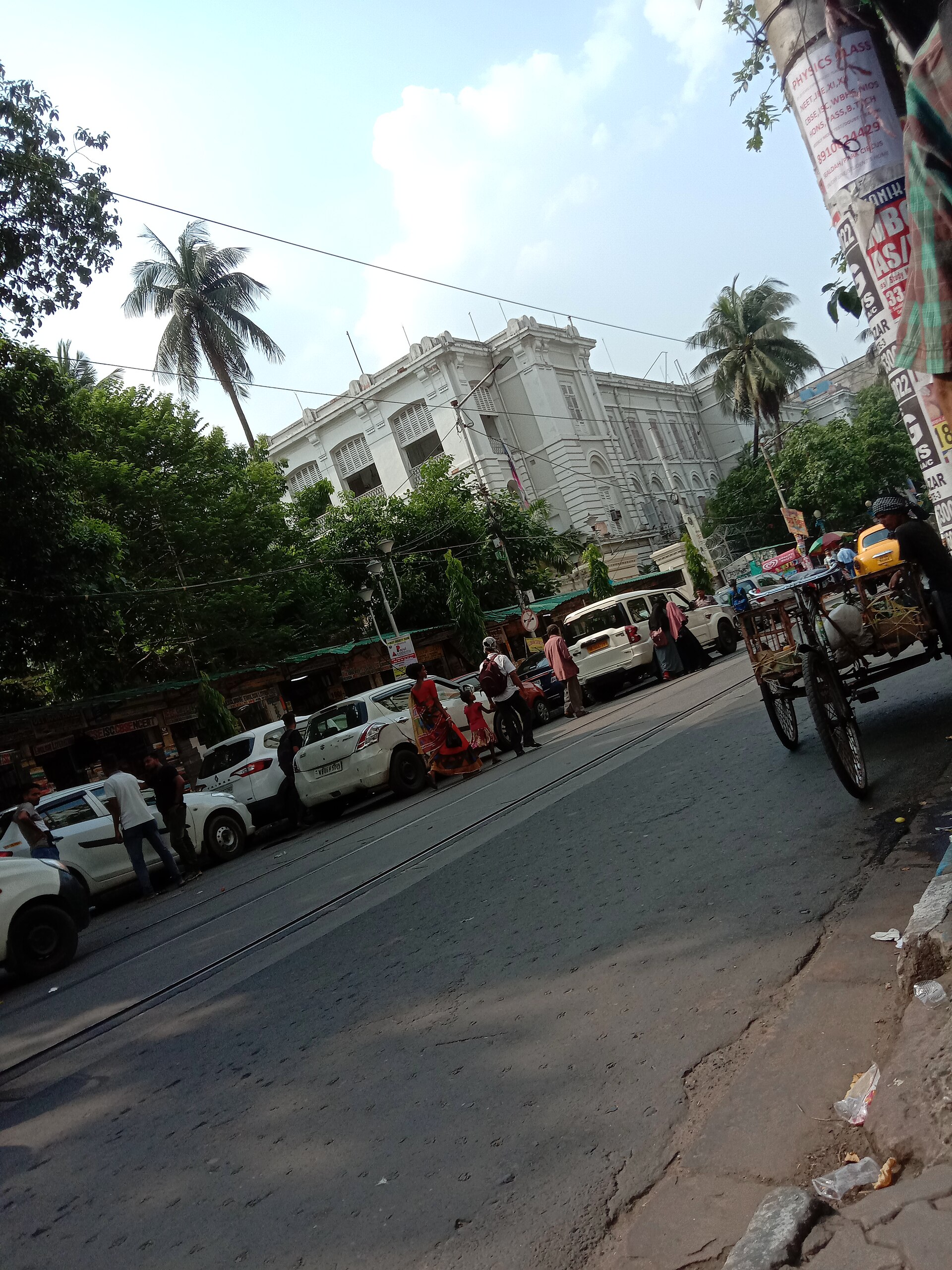 Kolkata Street Scene | Indian Press A bustling Kolkata street shows cars and a cycle rickshaw near buildings, reflecting urban life in India.
