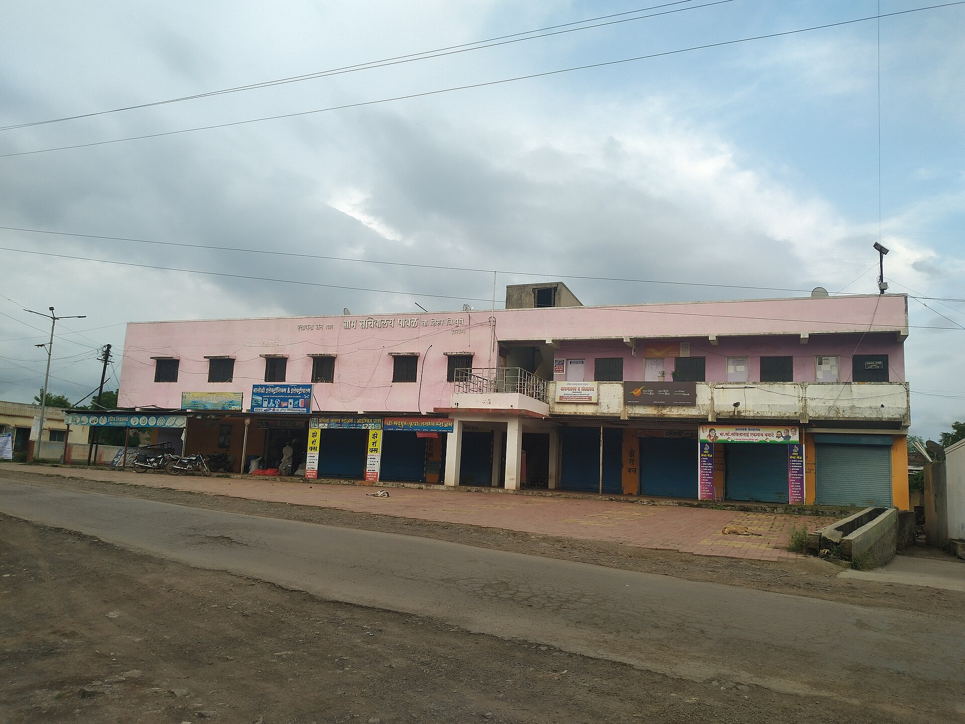 Pabal Gram Panchayat | Indian Press A rural street scene shows the Pabal Gram panchayat building and Shri Rameshwar Vapar Bazar shops, illustrating Panchayati.