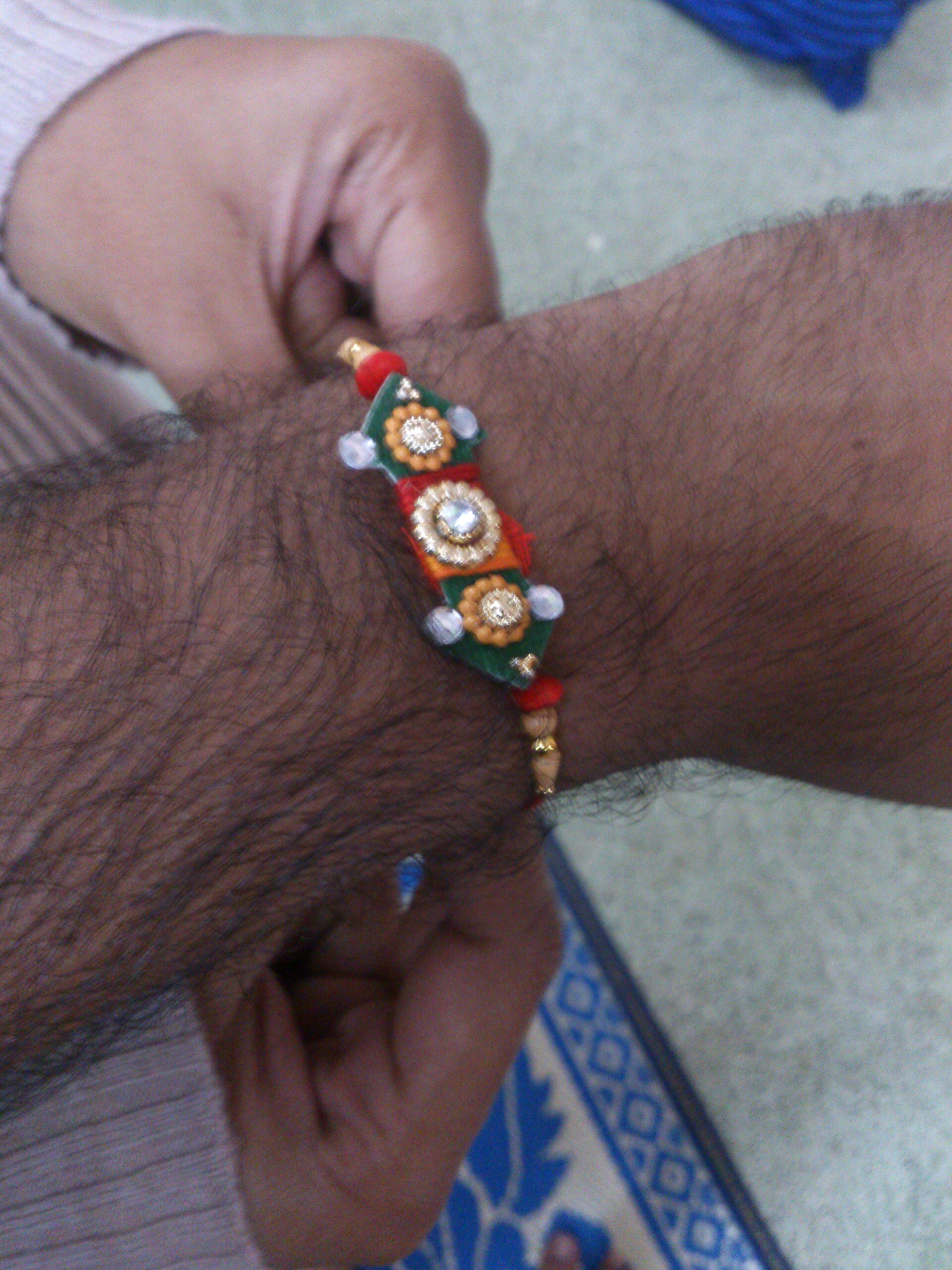 A man’s wrist displays a colorful Rakhi bracelet during the Raksha Bandhan festival, celebrating sibling bonds.